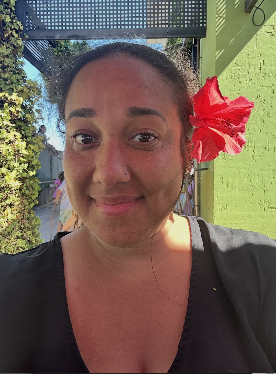 Erica Rivera outdoors in Spain with a red hibiscus flower